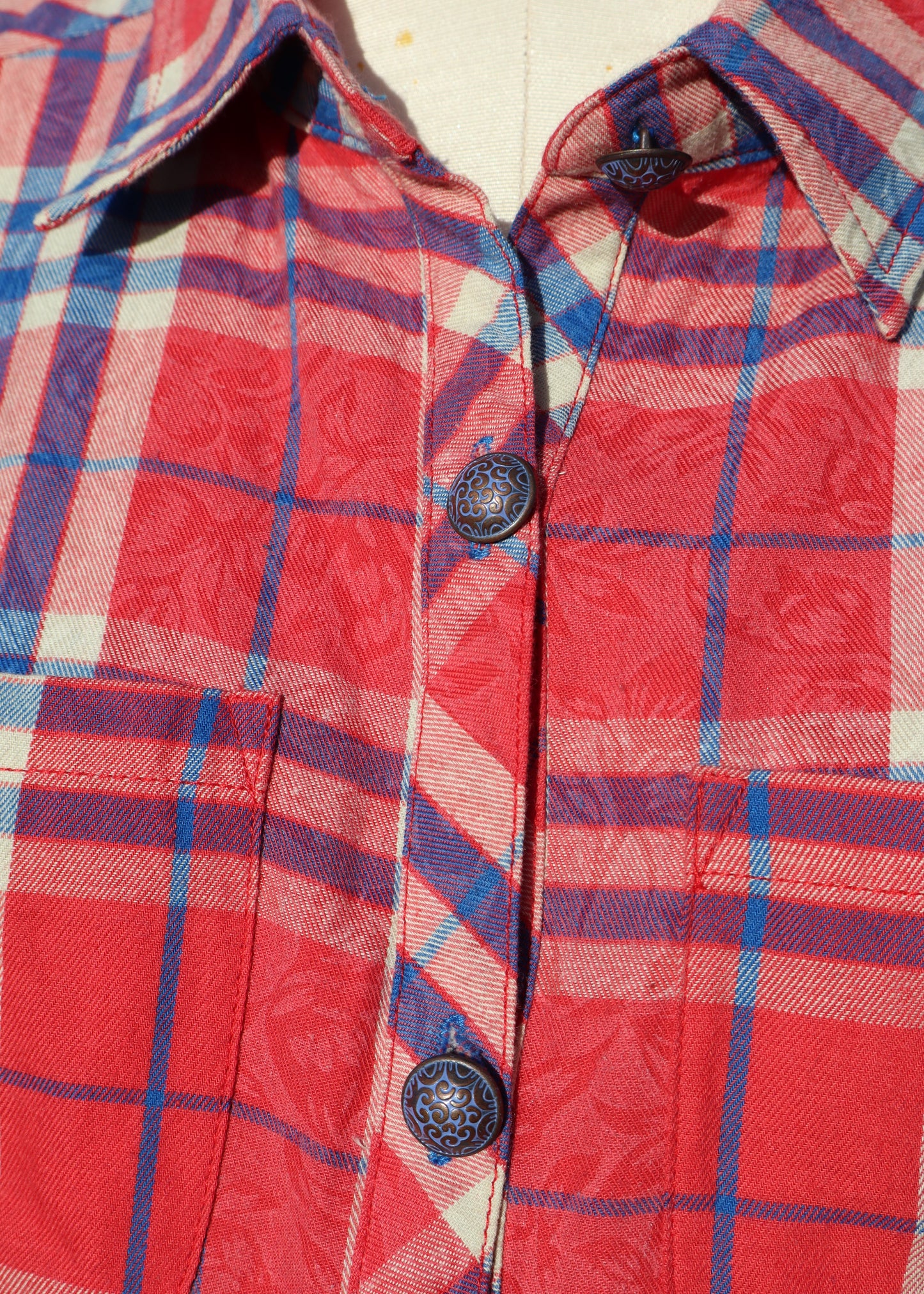 Red and blue plaid shirt with buttons on a plain background