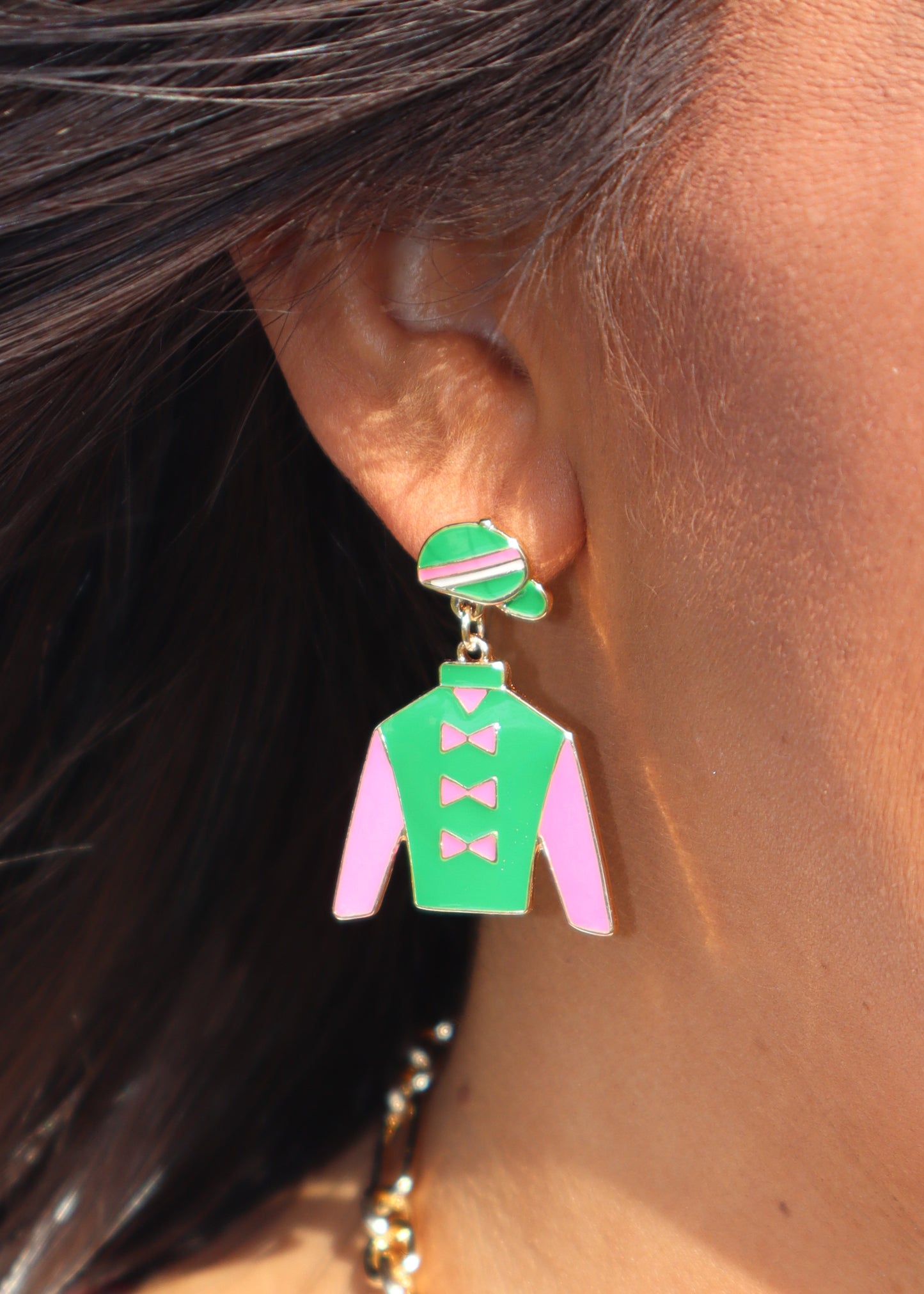 Kelly green and bubblegum pink jockey silk cutout stud earrings on a woman