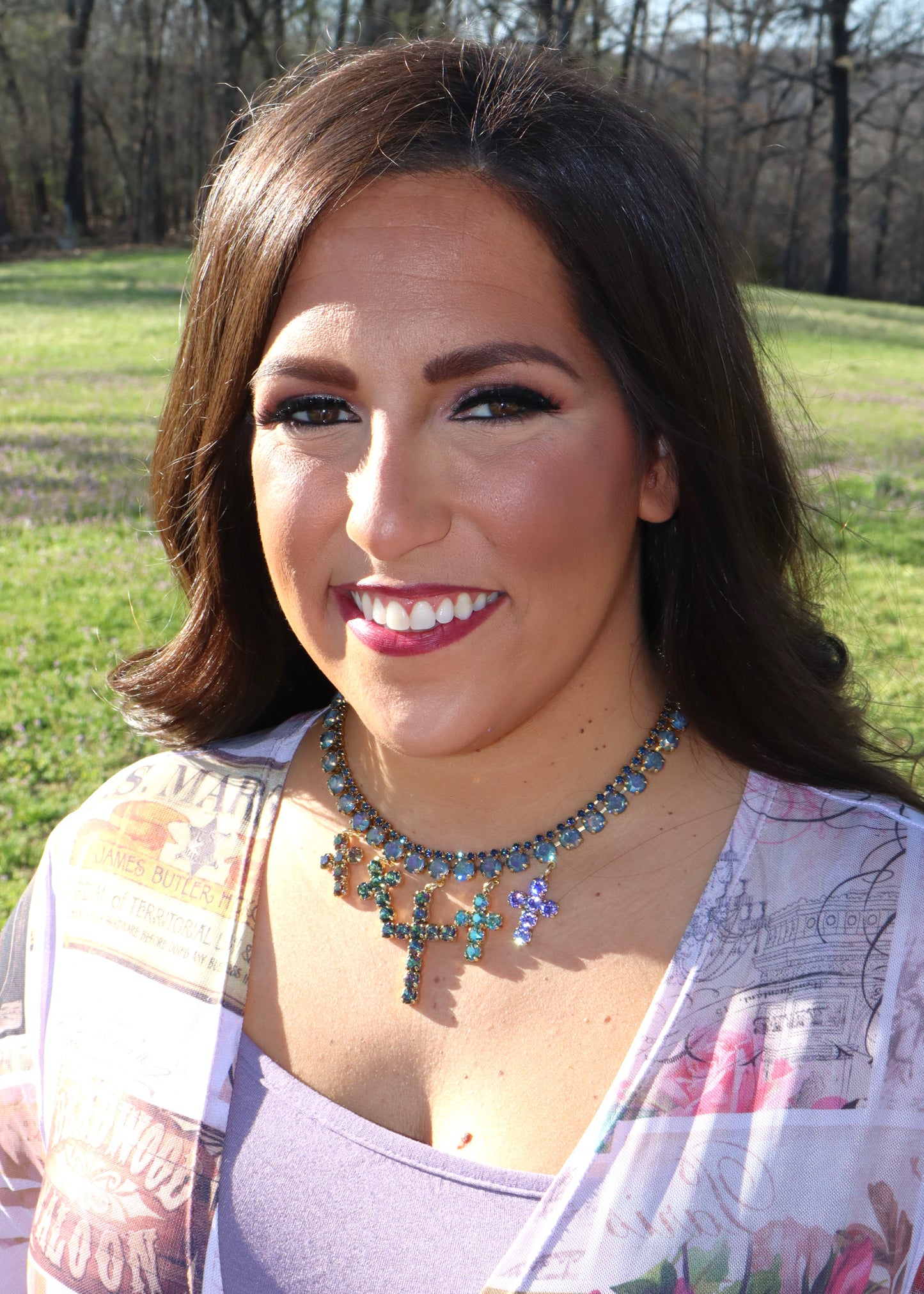 Woman wearing a 5 crosses colorful necklace standing outdoors in a grassy area