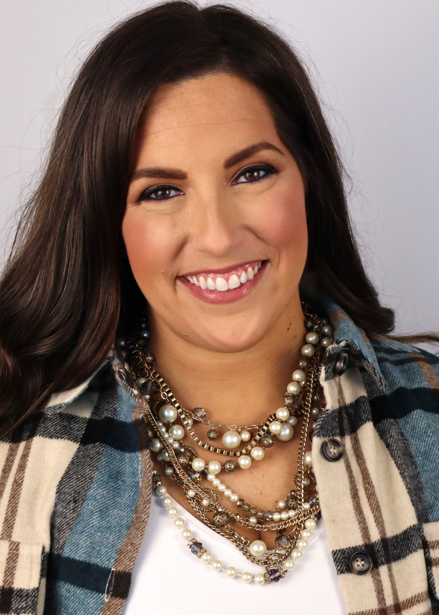Close-up of a woman wearing a plaid shirt with a multi-strand bronze and ivory detailed necklace