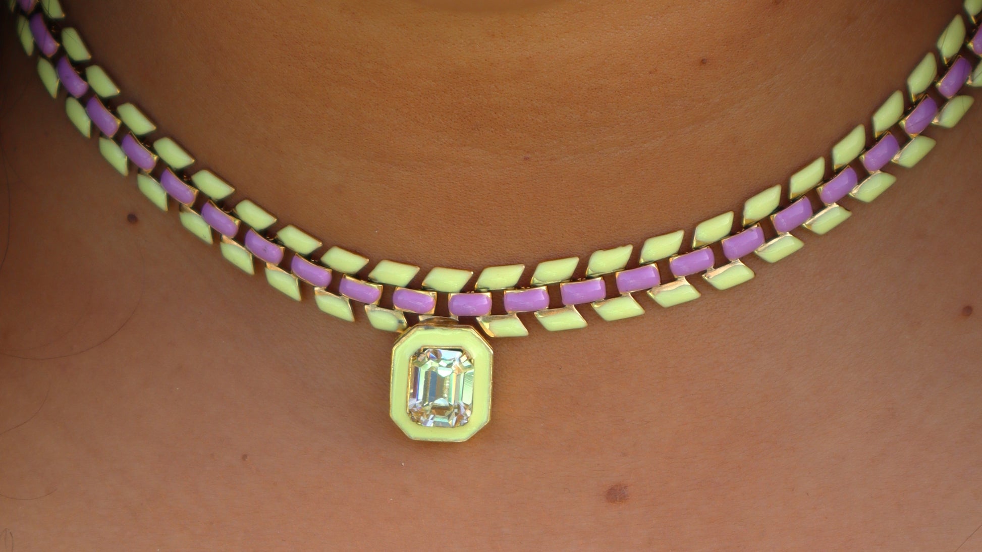 Woman wearing a purple and yellow painted gold-plated chain necklace with a center Swarovski crystal pendant.