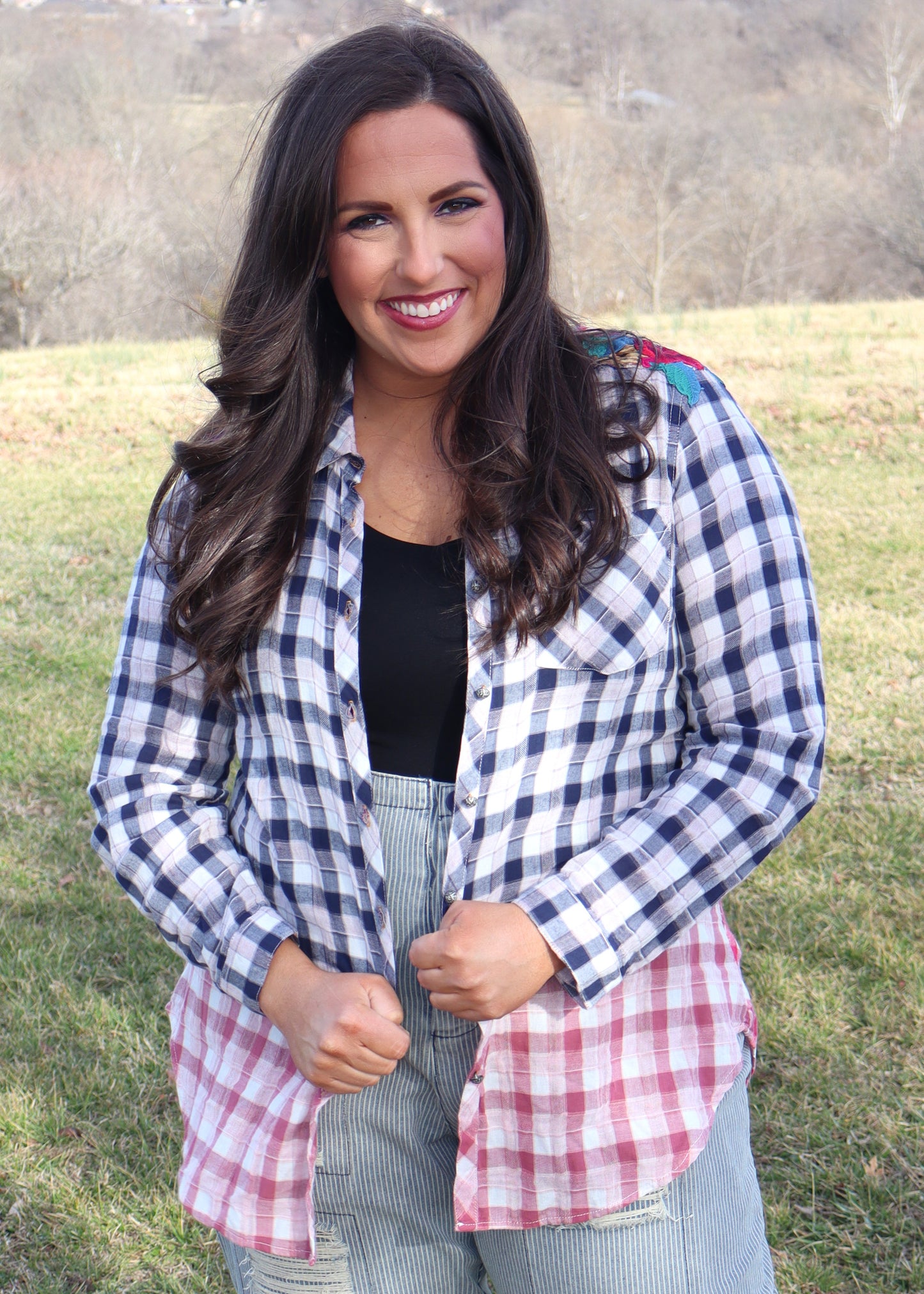 Woman wearing floral velvet applique-details on a plaid shirt with navy to red ombre effect while standing outside