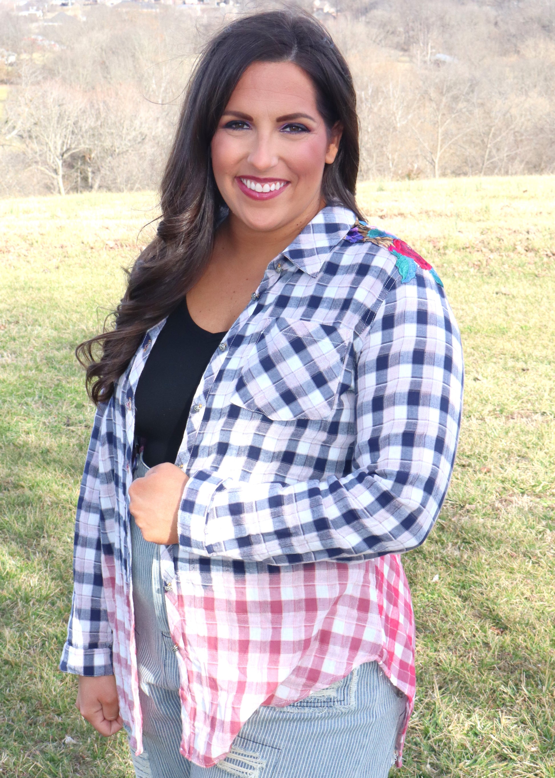 Woman wearing floral velvet applique-details on a plaid shirt with navy to red ombre effect while standing outside