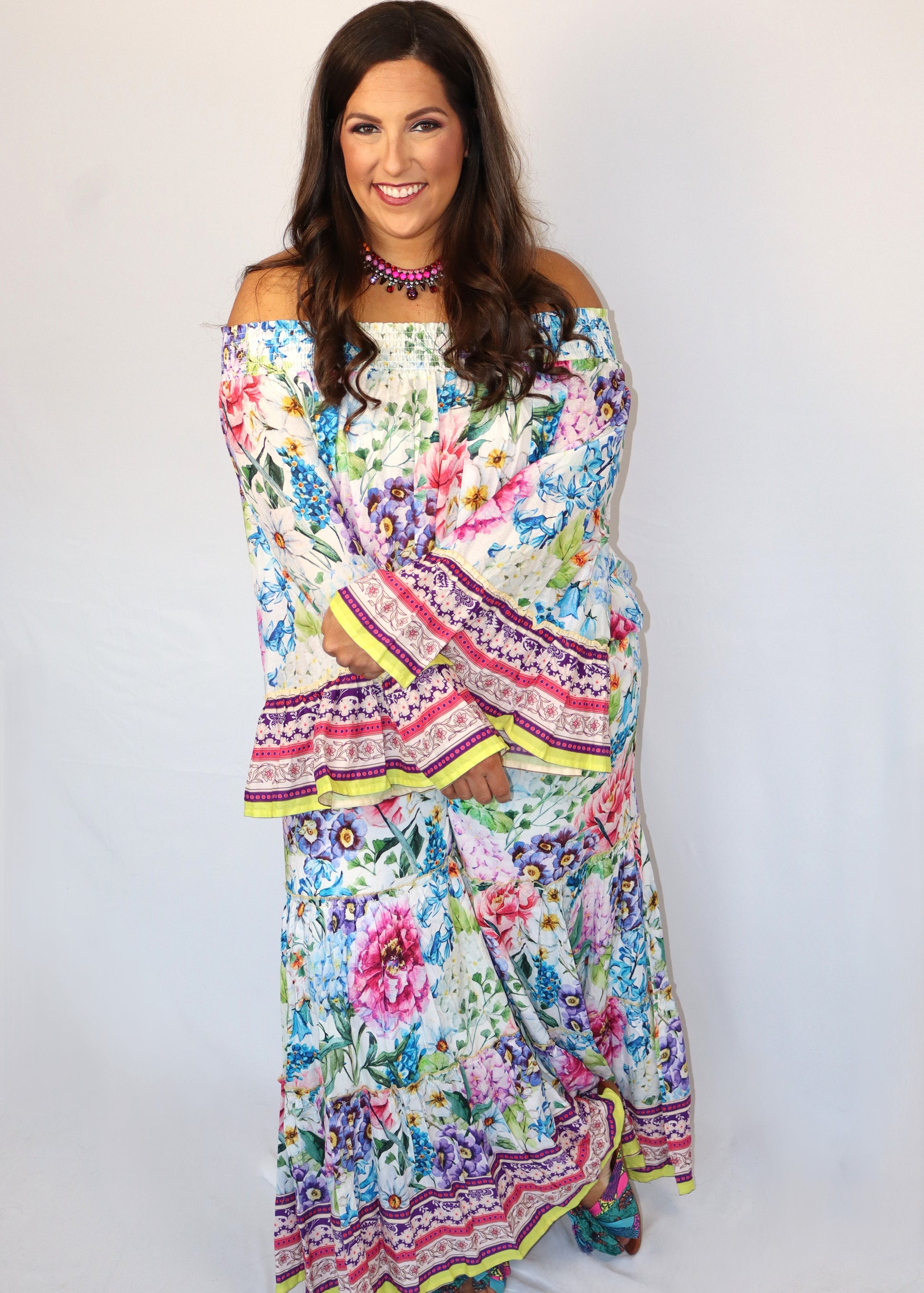 Woman wearing a matching floral blouse and flowy pants against a white background