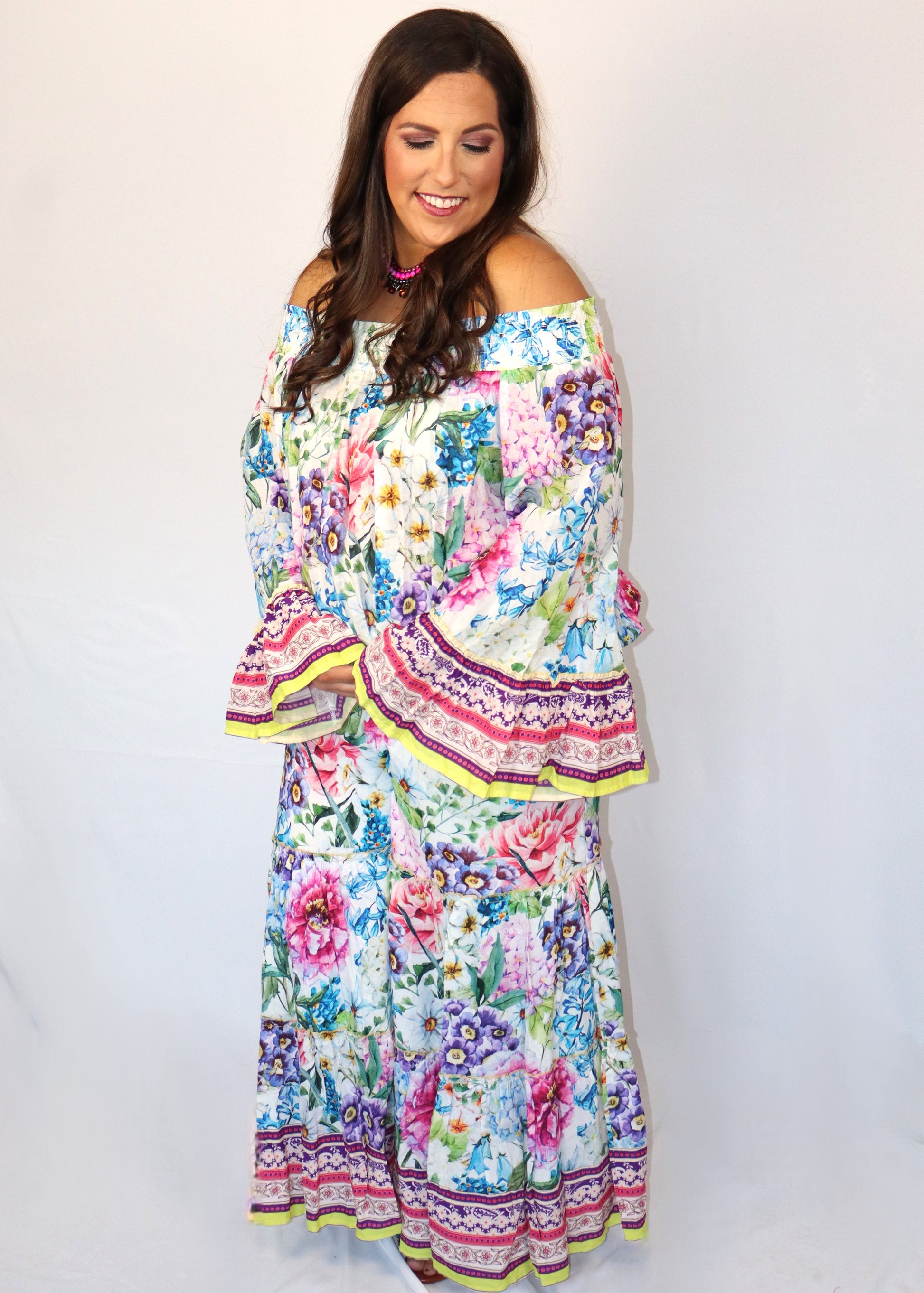 Woman wearing a matching floral blouse and flowy pants against a white background