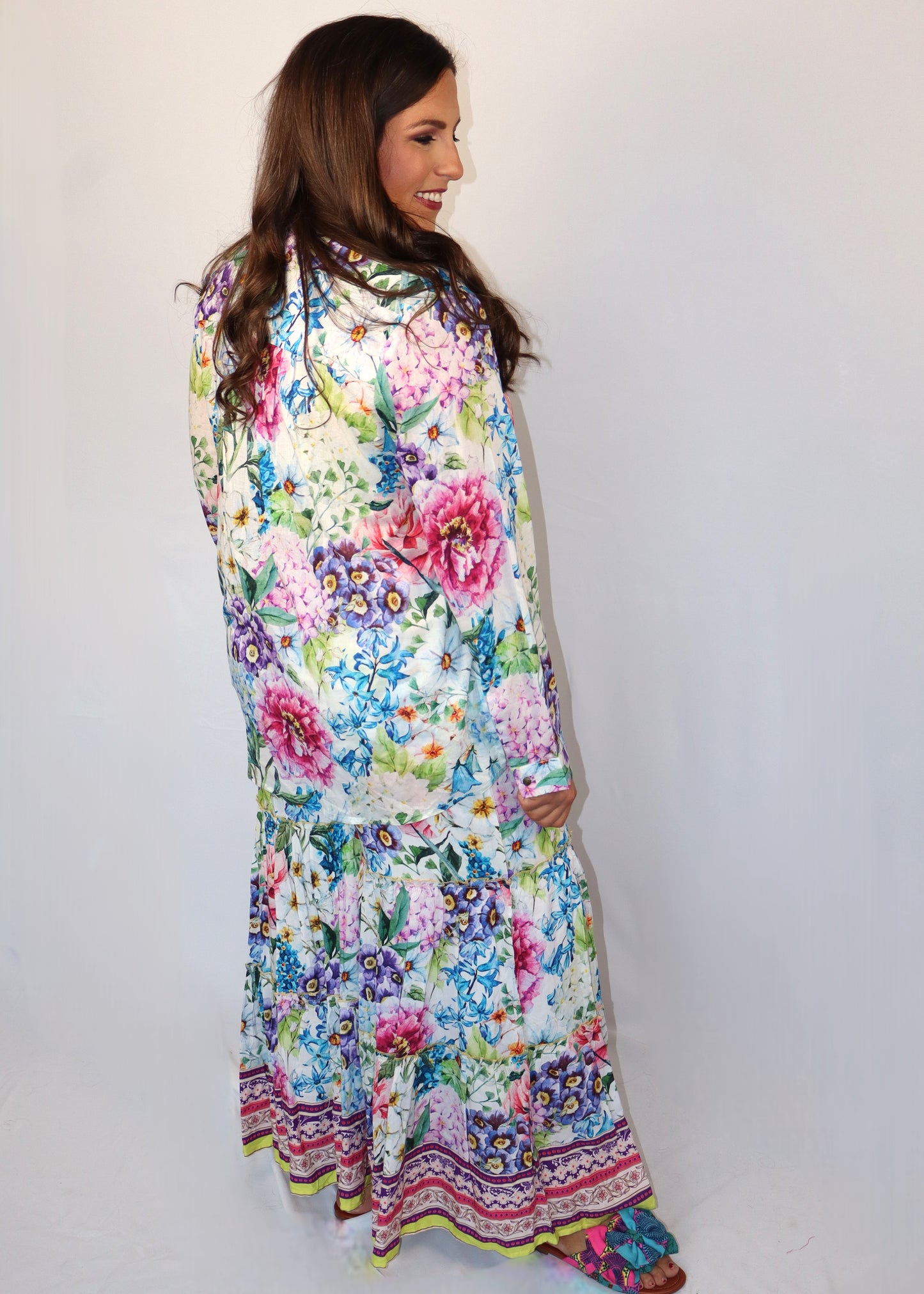 Woman wearing a matching floral blouse and flowy pants against a white background