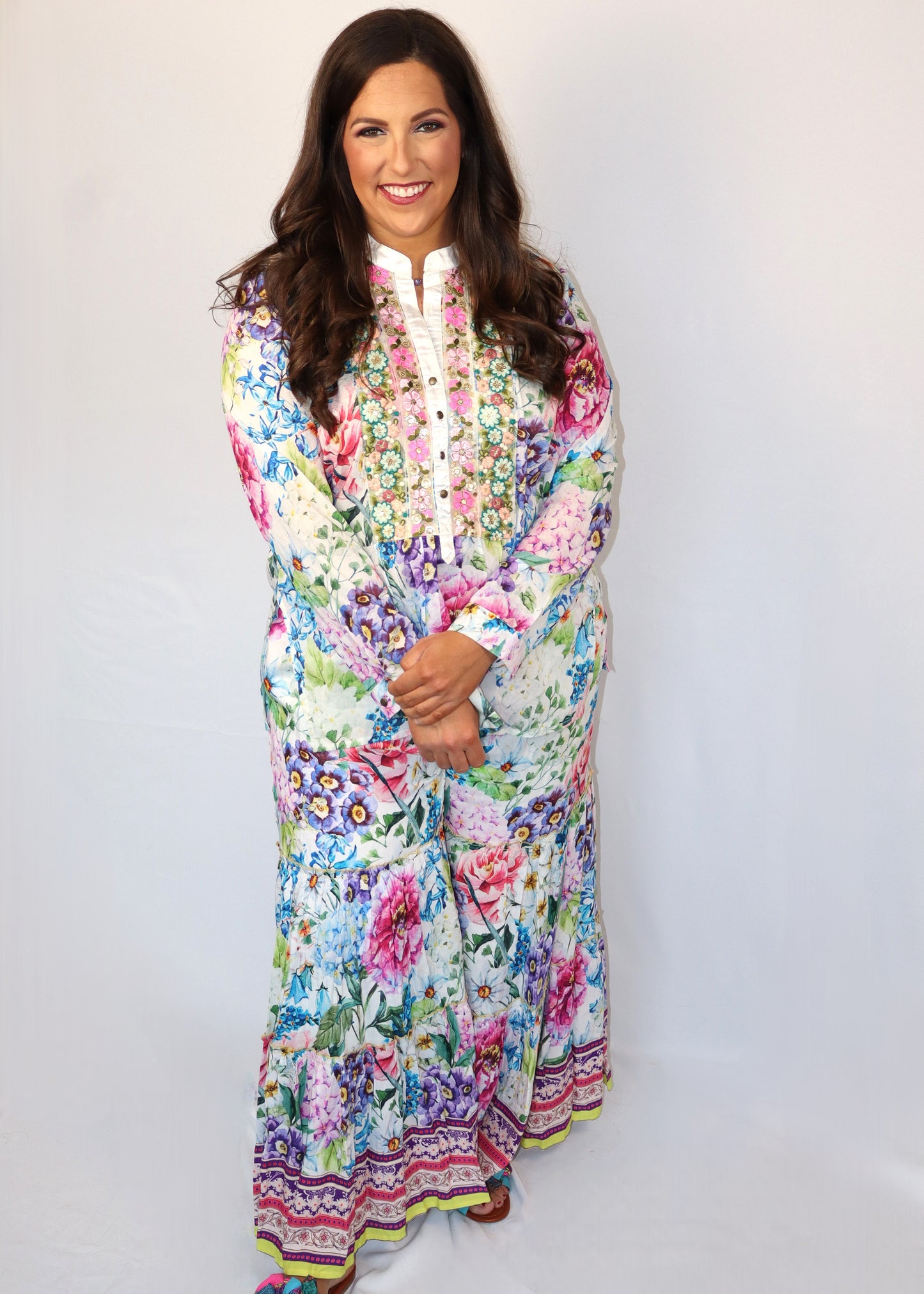 Woman wearing a matching floral blouse and flowy pants against a white background