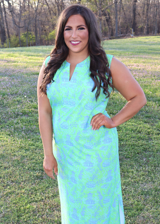 Woman wearing a blue and green dress standing in a grassy field.