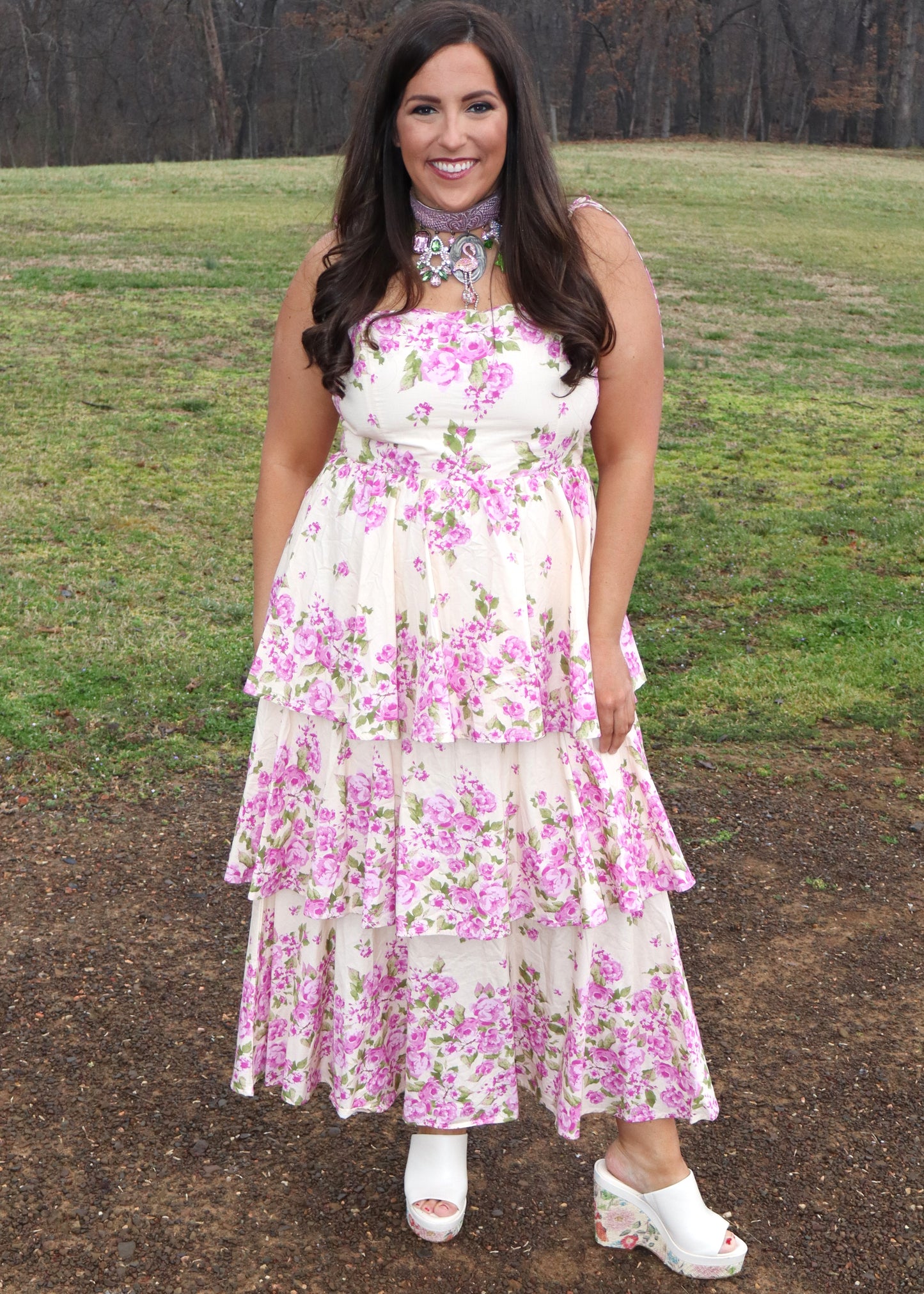 Woman wearing a floral dress standing in a grassy field.