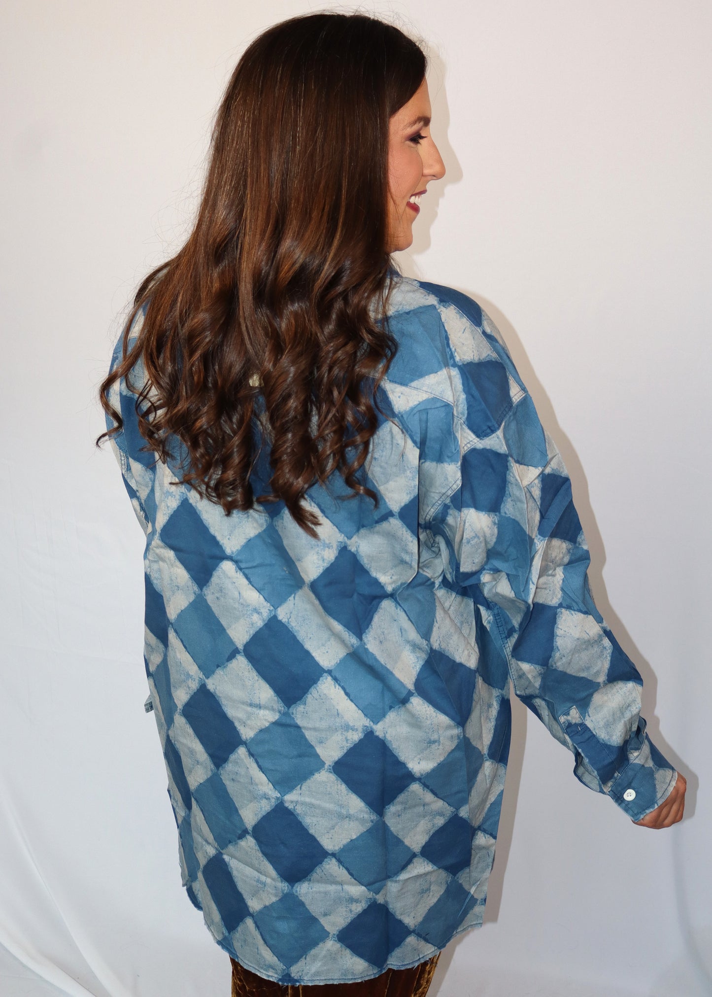 Woman wearing a blue and white checkered shirt against a plain background