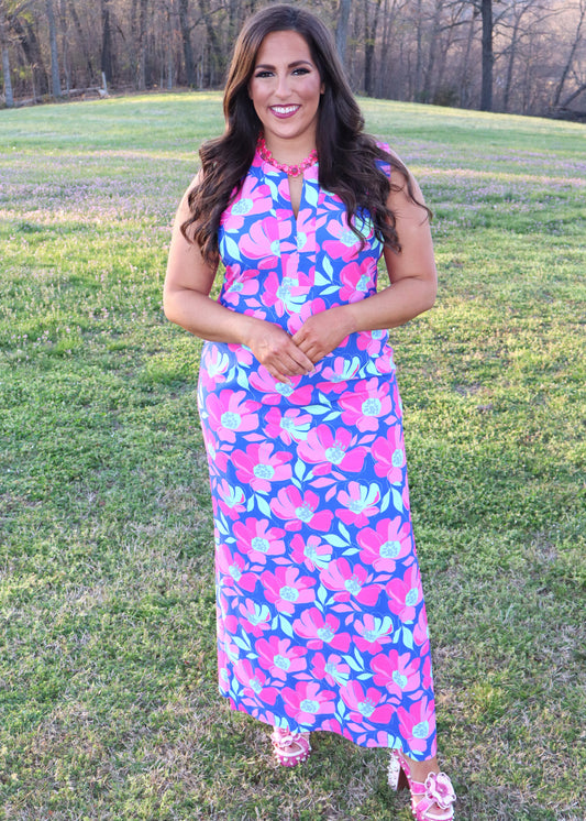Woman wearing a colorful floral dress standing in a grassy field.