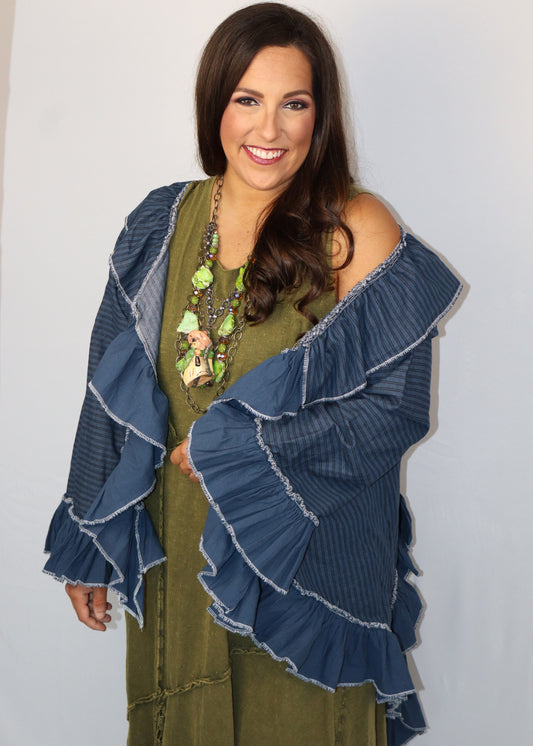 Woman wearing a blue ruffled cardigan over a green dress against a plain background